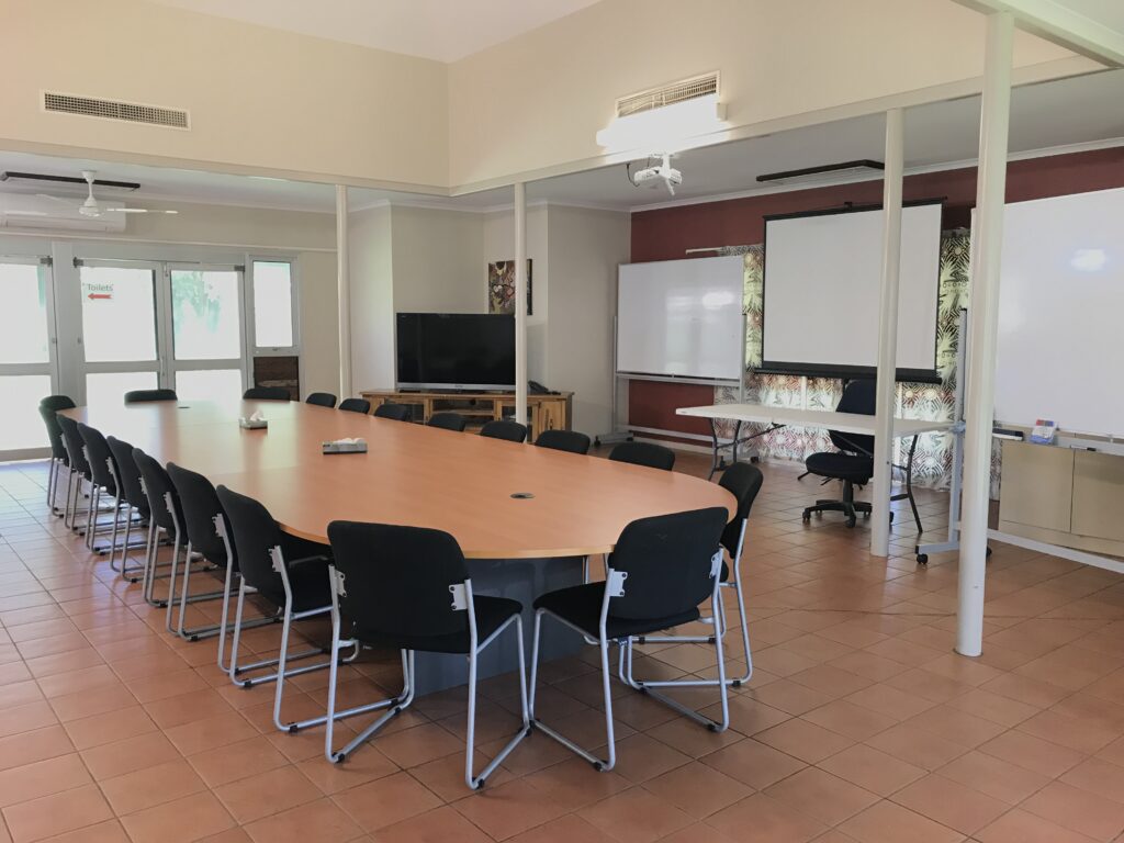 meeting table with chairs. TV and whiteboard close by.