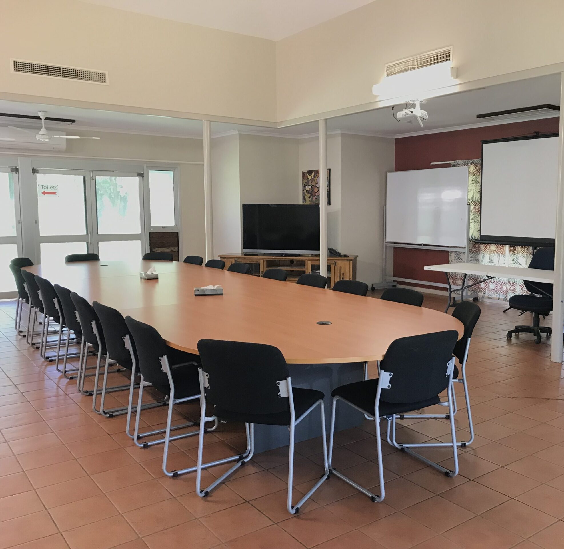 Meeting table with chairs. TV and whiteboard close by.